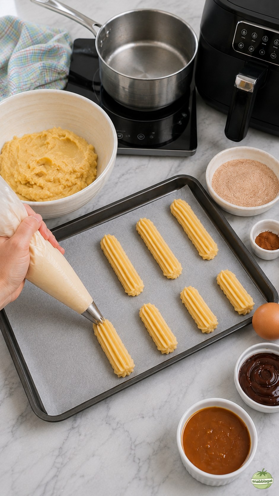 Churros spritsas i räfflade längder på bakplåtspapper hemma i köket
